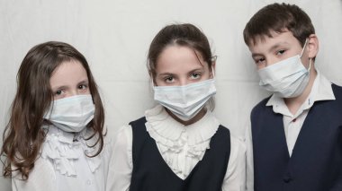 Coronavirus covid-19 salgını salgın hastalık sağlık hizmetleri konsepti okul üniformalı çocukların hastanede maske takması.