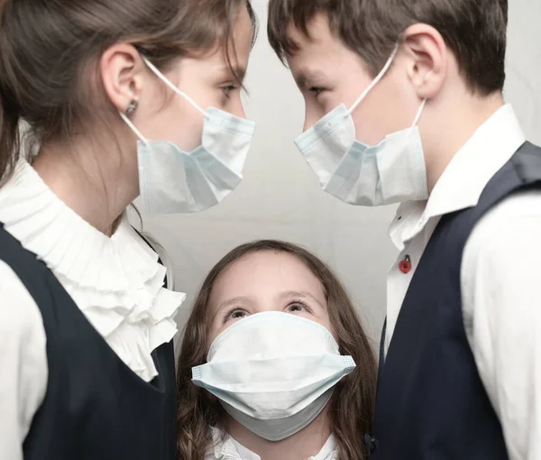 Covid-19 Koncepcja przeniesienia wirusa koronawirusu wirusa grypy troje małych dzieci w maskach medycznych i uniformie szkolnej — Zdjęcie stockowe