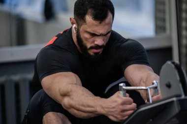 güçlü sakallı adam spor salonunda antrenman yapıyor.