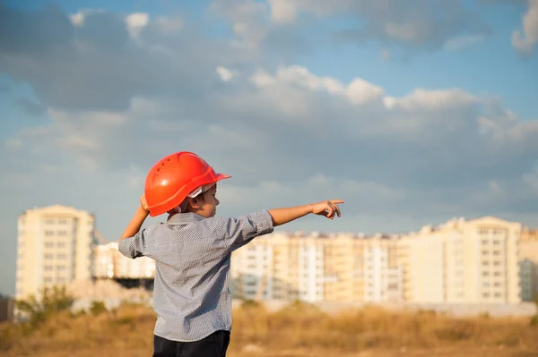 Один Маленький Мальчик Строитель Оранжевом Шлеме Указывая Пальцем Зданию Закате — стоковое фото