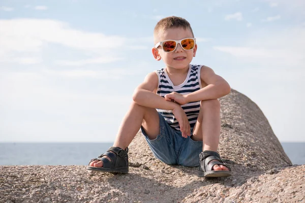 Kleine Jongen Een Vest Zonnebril Zittend Golfbreker Blok Achtergrond Van — Stockfoto