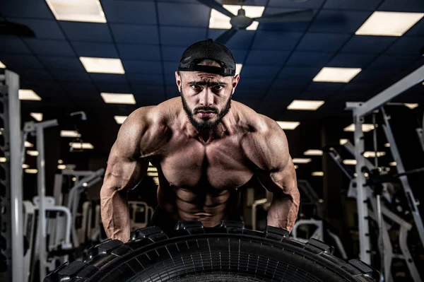 crossfit indoor gym training with truck tire of young handsome strong athlete male lifting heavy weight