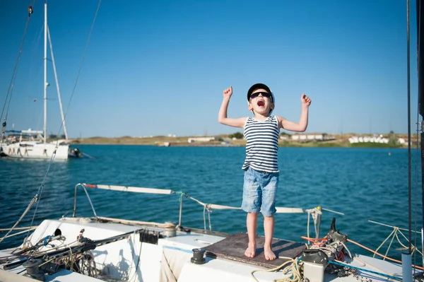 Felice bambino caucasico attivo in cappello da marinaio urlando con gioia sul bordo bianco yacht durante le vacanze estive di viaggio — Foto Stock