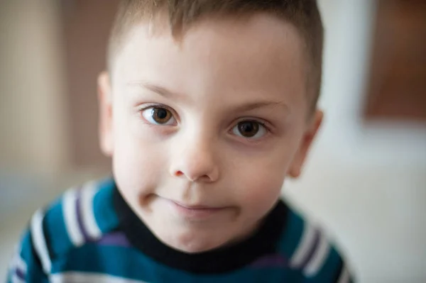 Эмоции умственная путаница улыбка на маленьком кавказском ребенке в свитере во время самоизоляции — стоковое фото
