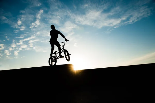 Jong actief sport man op de fiets op stedelijke straat op de zomer zonsondergang blauwe hemel — Stockfoto