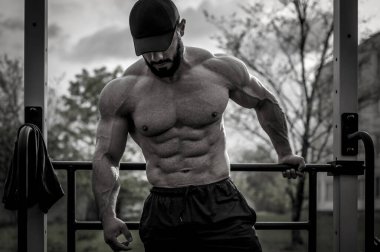 Yakışıklı genç sporcu sakallı adam spor salonunda vücut egzersizi yaparken şapkalı.