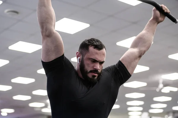 Strong muscular young bearded caucasian man in black jersey during rest in training gym workout — Stock Photo, Image