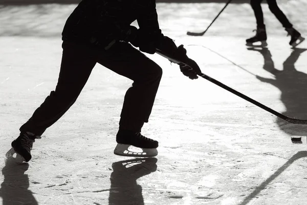 men play hockey on the rink during the day