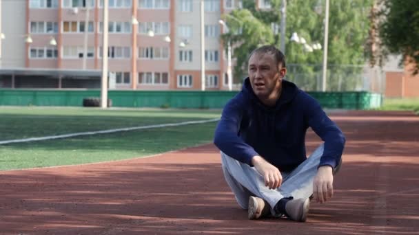 Atletisk sportsman vilar efter idrotten i parken och ser — Stockvideo