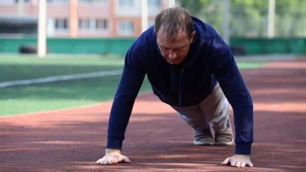 Hombre haciendo ejercicio en un estadio al aire libre. Gimnasia matutina . — Vídeo de stock