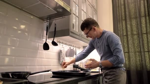 Ο άνθρωπος προετοιμασία πίτσα στην κουζίνα στο σπίτι. Πασπαλίζουμε με τριμμένο τυρί — Αρχείο Βίντεο