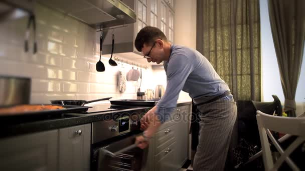 Der Mann mit der Brille legt Pizza in den Ofen — Stockvideo