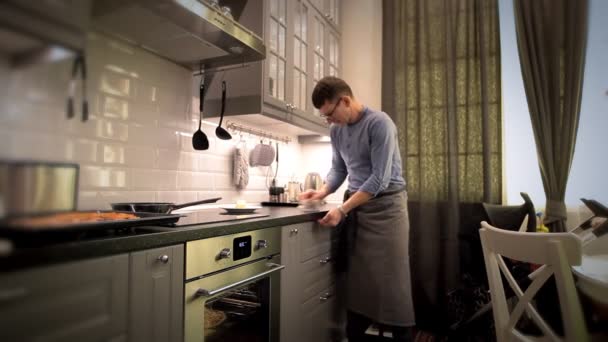 Un hombre elimina los escombros de la mesa después de cocinar — Vídeo de stock