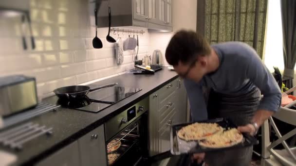 O homem de óculos põe na pizza de forno — Vídeo de Stock