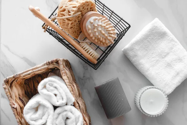 On a marble background a set of various bath accessories. Terry towel, soap, comb, oil, shampoo, loofah washcloth and candles. The view from the top Stock Picture