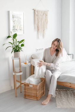 Kız odayı temizler, yatağı yapar. Yatak örtüsünü kıvırıyor. Parlak oda içi