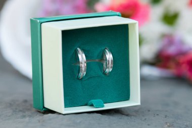 Bir buket beyaz ve pembe çiçeğin yanında alyans.