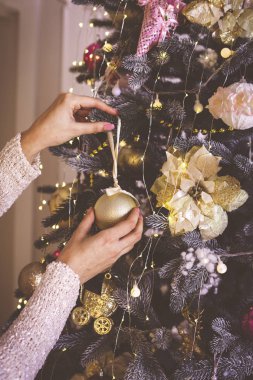 Kadın elleri Noel ağacını güzel cam toplarla süslüyor..