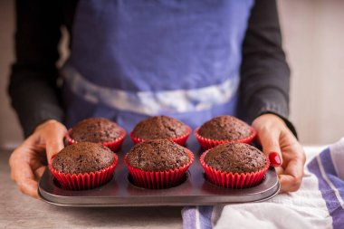 Çikolatalı kek yapıyorum. Güzel kadın elleri bir kap kekle fırın tabağını tutuyor..