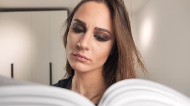 Concentrato giovane ragazza lettura libro a casa su sfondo interno 4k — Video Stock