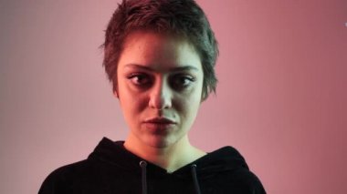 Yakın plan dişi ergen parmağını dudaklarına koyar, bir sessizlik jesti ya da neonun arka planına karşı bir sır. 4k