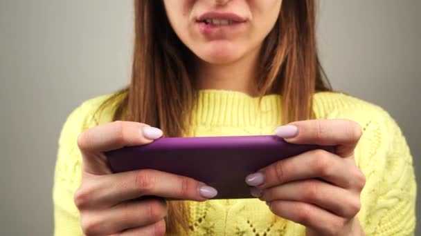 Kobieta gra tablet lub smartfon w domu dziewczyna gra w grę na telefon komórkowy ona torebki usta i usta 4k — Wideo stockowe