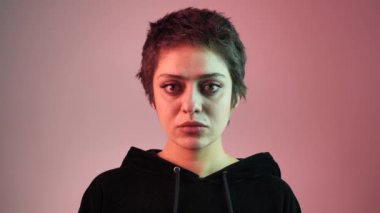Kısa saçlı, neon ışınlı genç bir kızın portresi. Kız doğrudan kameraya bakıyor. 4K
