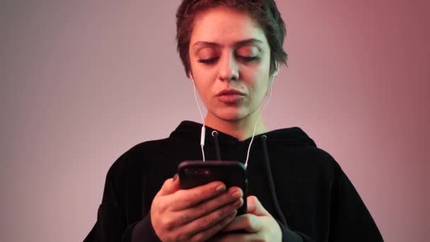 Chica de corte de pelo corto escucha música y clics smartphone 4k — Vídeo de stock