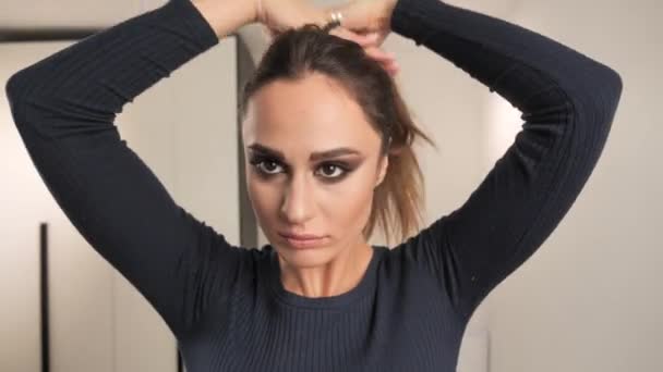 Modèle femme au foyer en vêtements de maison attachant ses cheveux dans un chignon. 4k — Video