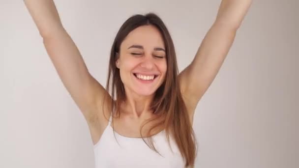 Ung vacker flicka visar aktivt glädje, leenden och viftar med händerna, efter att ha lärt sig att hon vann på lotteri. Porträtt på en vit bakgrund. 4k — Stockvideo
