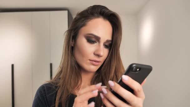 Schöne Modell mit Make-up-Nachricht auf dem Smartphone lesen und extrem glücklich, Lottogewinn. 4k — Stockvideo