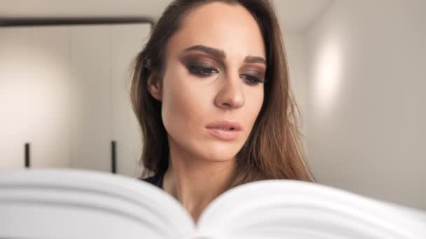 Koncentrerad ung flicka läsa bok hemma på interiör bakgrund 4k — Stockvideo