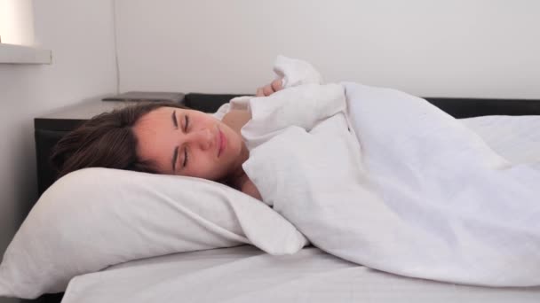 ผู้หญิงสวยตื่นขึ้นจากการนอนหลับและไม่ต้องการออกจากเตียง 4k — วีดีโอสต็อก