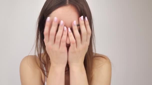 Meisje met natuurlijke make-up bedekt haar gezicht met handen en glimlacht 4k — Stockvideo