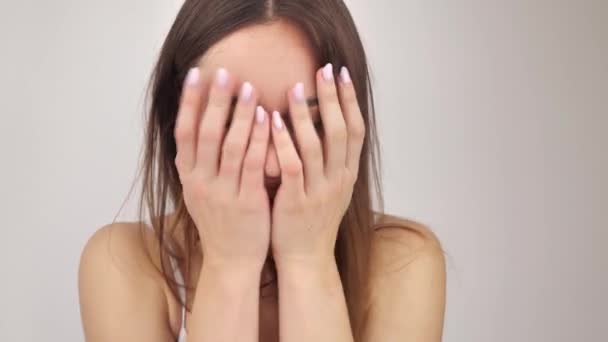 Ragazza con trucco naturale copre il viso con le mani e sorrisi 4k — Video Stock