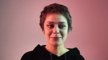 Kısa saçlı, neon ışınlı genç bir kızın portresi. Kız doğrudan kameraya bakıyor. 4K