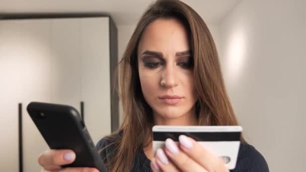 Una mujer feliz y sonriente haciendo un pago con tarjeta a través del teléfono móvil para pagar las facturas. 4k — Vídeo de stock