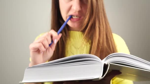 Молодая очаровательная студентка читает книгу, пытаясь запомнить текст 4k — стоковое видео