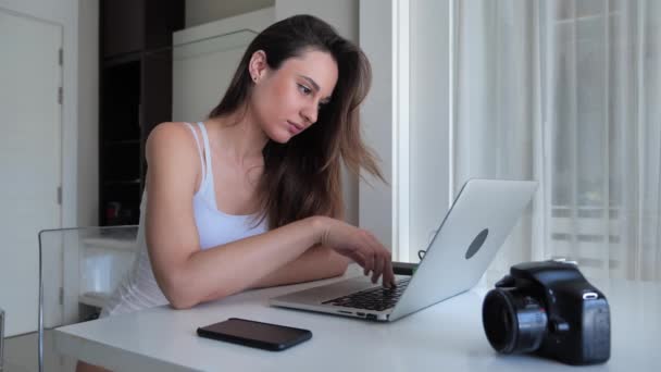 Mujer creativa joven fabricante de clips sentado en un apartamento con interior moderno y mirando a una pantalla de ordenador 4k — Vídeos de Stock