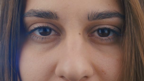 Közelkép egy barna szemű nőről. A kamerába néz. 4k — Stock videók