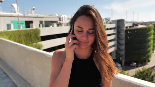 Close up of smiling young elegant bissneswomanl with deep brown eyes in black dress trying to buy something pleasant with her smartphone Urban city background.Movimento lento 4k — Vídeo de Stock