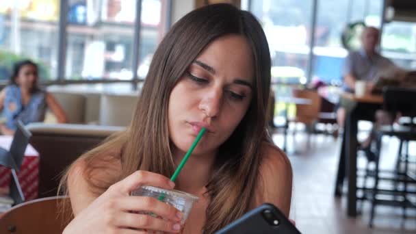 一个可爱女孩的肖像，她喝着咖啡，点击智能手机4k — 图库视频影像