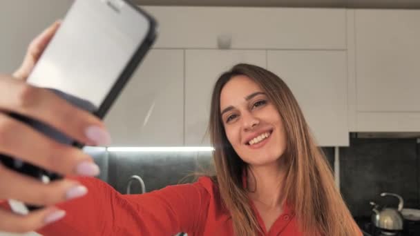 Красива дівчина бере селфі на чорному телефоні на фоні сучасного інтер'єру 4k — стокове відео