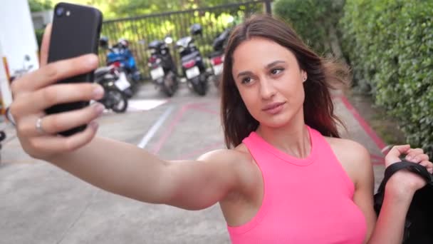 Fechar - up retrato jovem mulher sexy leva uma selfie no fundo de um estacionamento com motocicletas — Vídeo de Stock