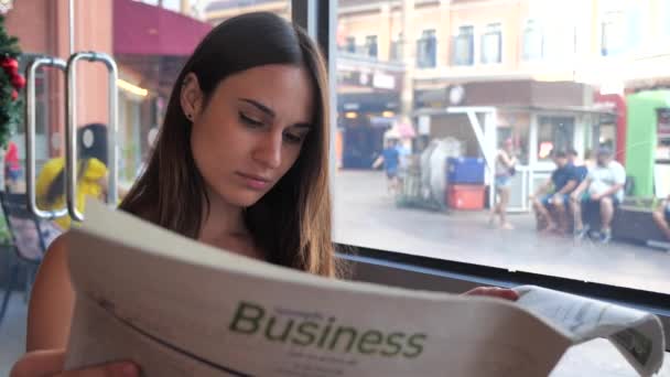 Jonge vrouw in een cafe zitten en lezen van een krant 4k — Stockvideo