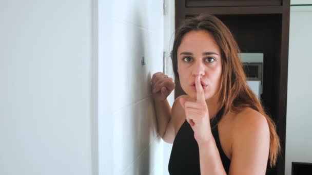 Paranoid woman is shocked looking into the peephole. The female wants to hide from an unexpected guest and shows shh. 4k — Stok video