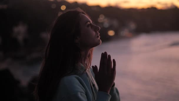 Vacker flicka ber tittar upp på lila himmel med hopp, närbild. Silhuett av ung kvinna drömmer tittar uppåt solnedgången utomhus. — Stockvideo