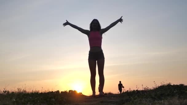 Mulher feliz levantou as mãos para cima desfrutar do pôr do sol em férias de viagem de verão. Felicidade e felicidade conceito de vídeo com a fêmea de alegria comemorando em silhueta. LOW MOTION 4k — Vídeo de Stock