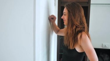 Paranoid woman is shocked looking into the peephole. The female wants to hide from an unexpected guest and shows shh. 4k