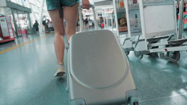 Woman stepping and roll suitcase on wheels. Woman walking with her suitcase along airport. Travel concept. Slow motion 4k
